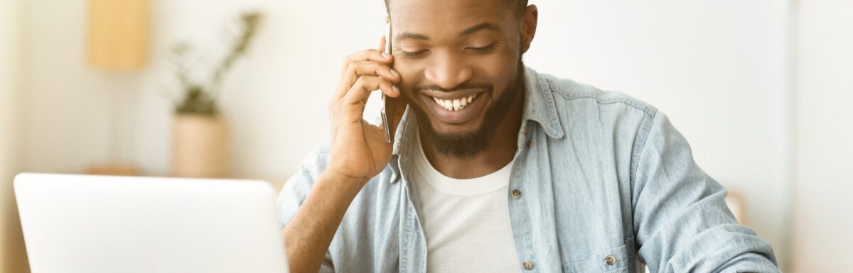 Cheerful african american businessman talking on phone and reading documentation